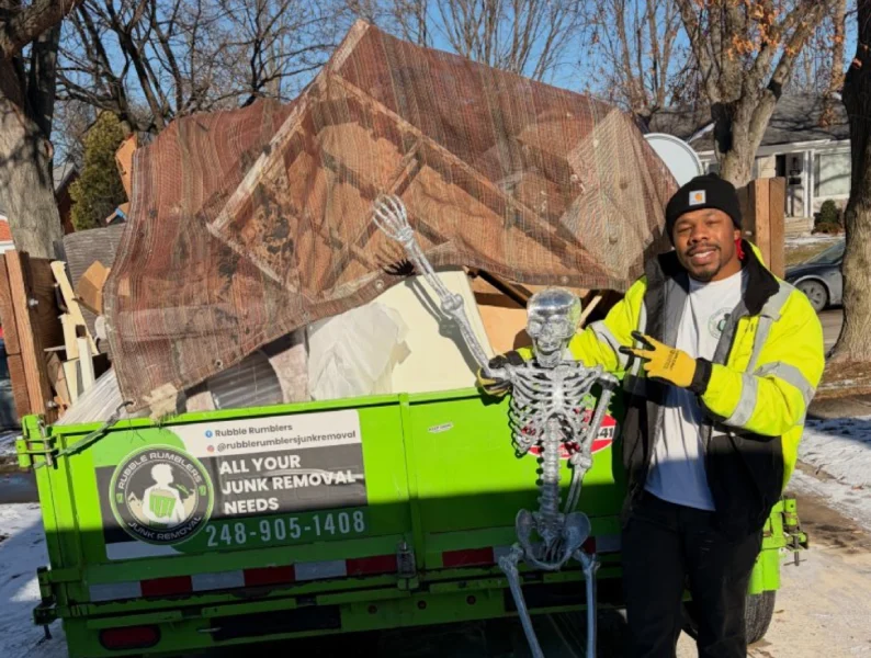 Man in yellow vest poses with skeleton next to junk removal dumpster Rubble Rumblers