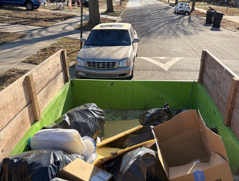 Debris and trash bags in a dumpster in front of a car on a residential street. Rubble Rumblers