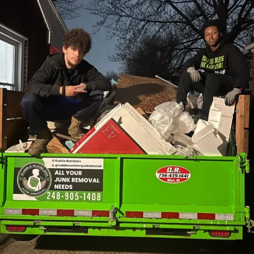 Junk removal service truck with two men posing, featuring Rubble Rumblers branding. Rubble Rumblers